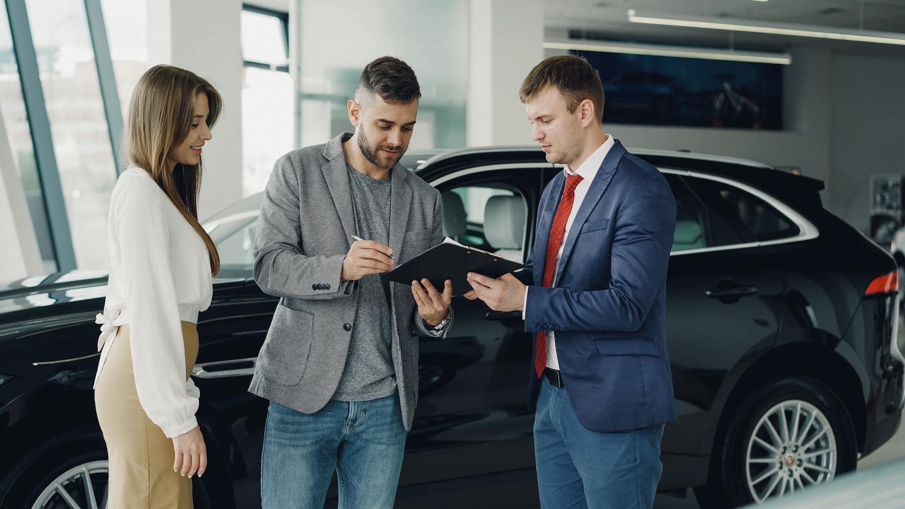Dealership managers reviewing service, sales, finance, and training documents in an operations meeting.