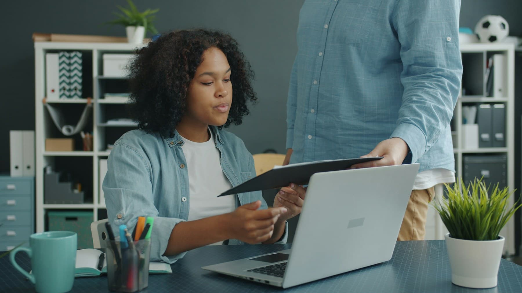 Two colleagues reviewing paper documents beside a laptop in an office workspace.