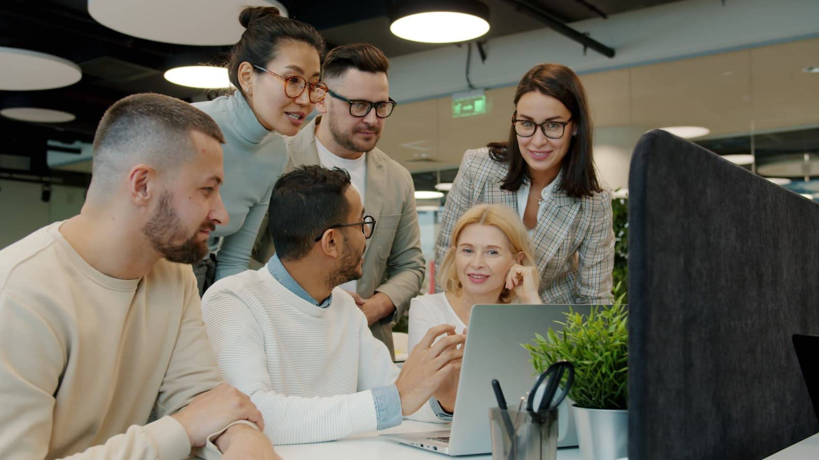 A team collaborating around a laptop in a bright office workspace.